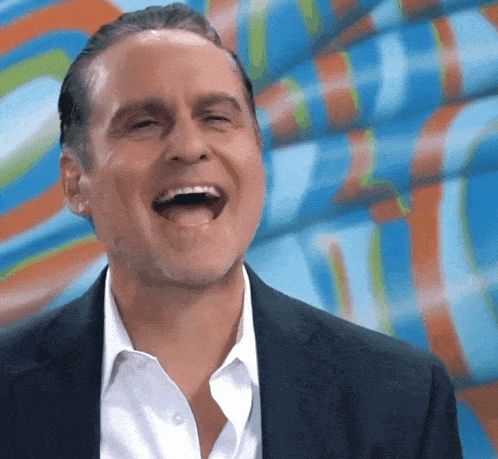 a man in a suit and white shirt is laughing