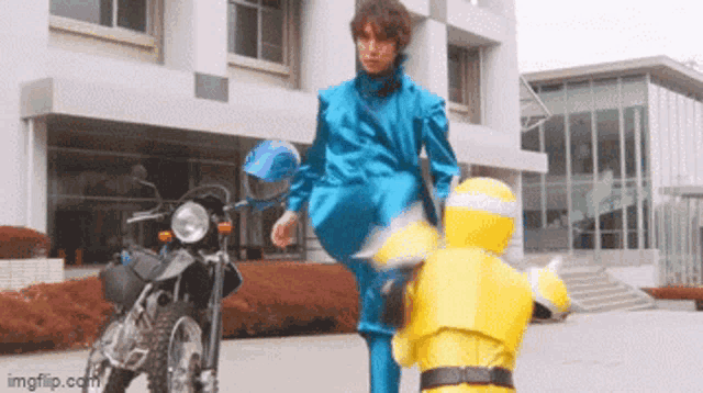 a man in a blue suit kicking a yellow robot on a motorcycle .