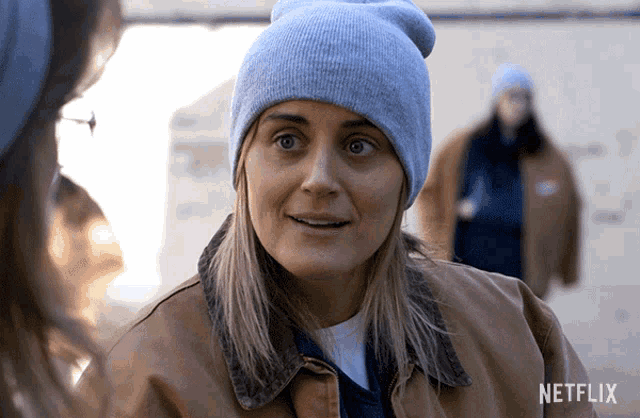 a woman wearing a beanie and a jacket with a netflix logo in the corner