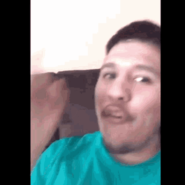a man with a mustache is sitting on a couch and making a face .