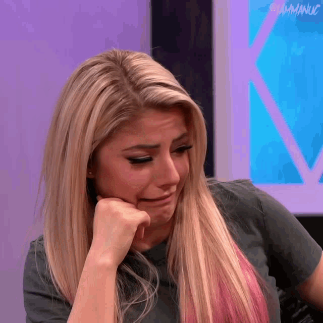 a woman with blonde hair and a gray shirt is crying