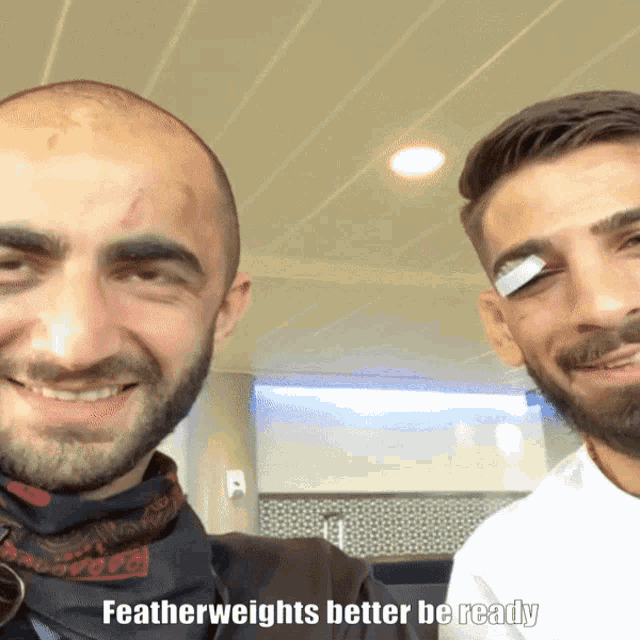 a man with a bandage on his eye is smiling next to another man with featherweights better be ready
