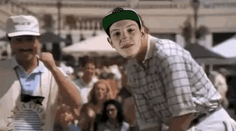 a young man wearing a green hat is standing in front of a crowd .