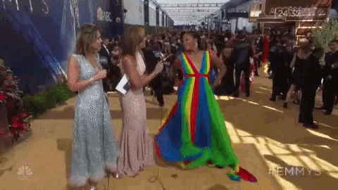 a woman in a rainbow dress is on the red carpet at emmys