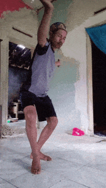 a man in a blue shirt and black shorts is standing on a tiled floor
