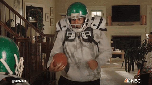 a man in a football helmet is holding a football in a living room