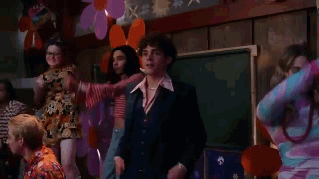 a group of people are dancing in a room with balloons and flowers .