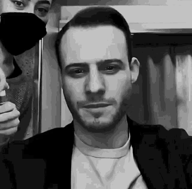 a man wearing a mask is standing next to another man .