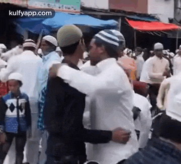 a man is hugging another man in a crowd of people .
