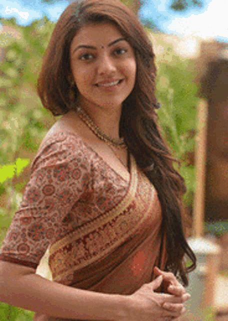 a woman wearing a blouse and a necklace is smiling for the camera