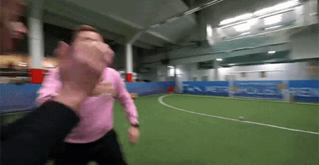 a man in a pink shirt is being held by another man