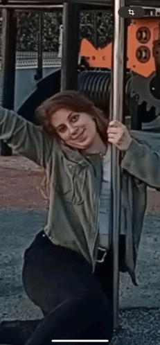 a woman in a green jacket is holding a pole in a playground