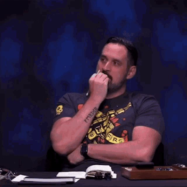 a man wearing a shirt that says shoot firs is laughing while sitting at a desk
