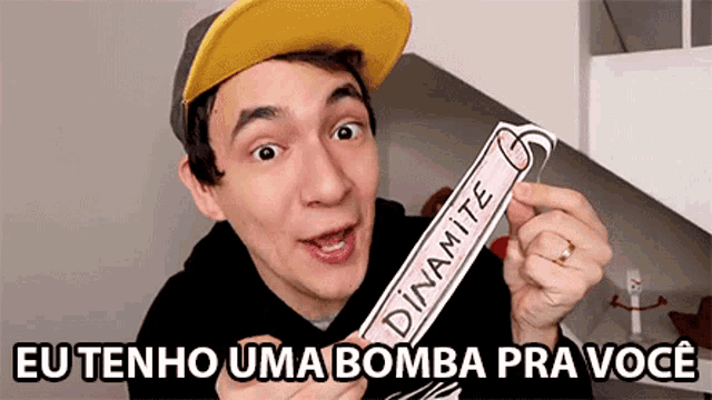 a man in a yellow hat is holding a paper bomb that says " eu tenho uma bomba pra você "