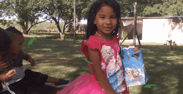 a little girl wearing a pink frozen shirt
