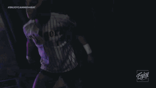 a man in a tigers jersey stands in front of a neon sign that says enjoy