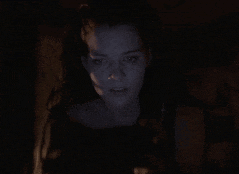 a woman in a dark room with a blue light behind her