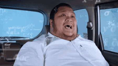 a man in a white shirt is sitting in the back seat of a car with math equations behind him