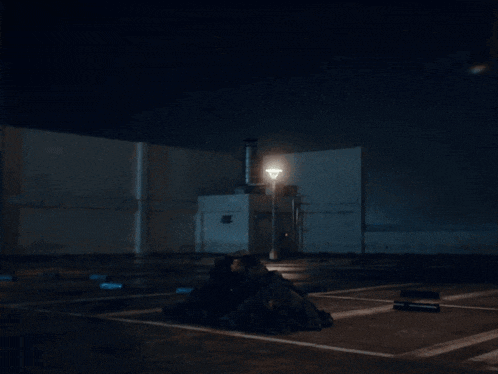 a man in a black jacket stands in a parking lot