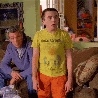 a boy wearing a yellow shirt that says cat 's cradle on it