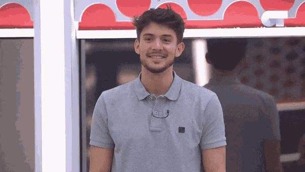 a man wearing a grey polo shirt smiles in front of a red polka dot curtain