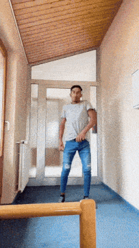 a man in a white shirt and blue jeans is standing in front of a glass door
