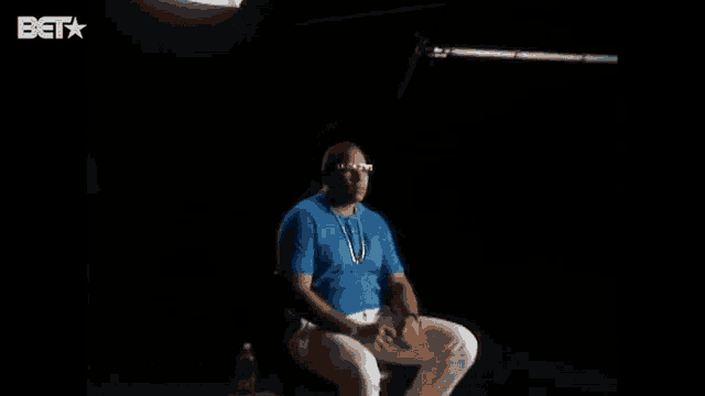 a man wearing sunglasses and a blue shirt with bet on the bottom right