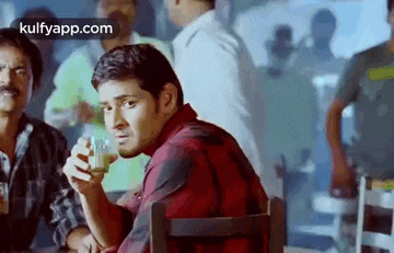 a man is sitting at a table holding a glass of milk .