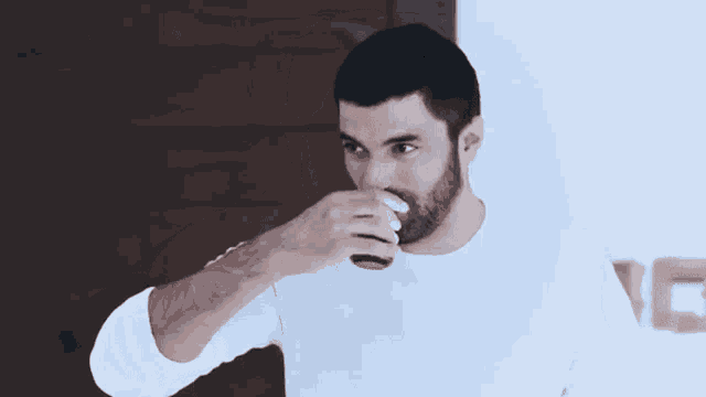 a man with a beard drinks from a cup