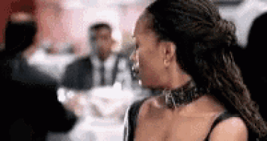 a woman wearing a choker is sitting at a table in a restaurant with people .