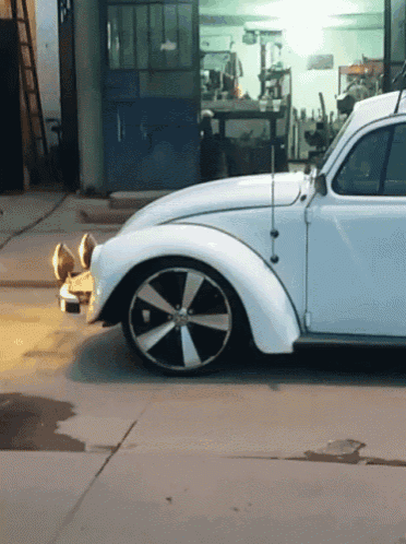 a white car with black and white wheels is parked in a parking lot