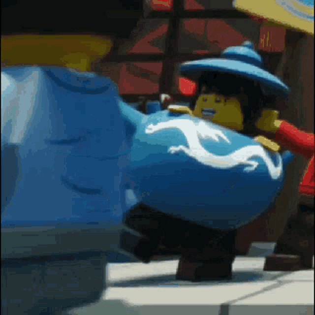 a lego character with a blue hat and a dragon on his shirt is standing on a sidewalk .