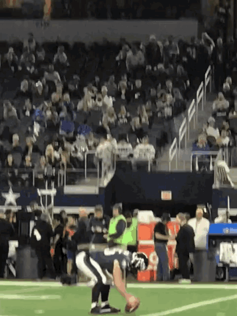 a football player is kneeling down on the field with a crowd behind him and a sign that says exit