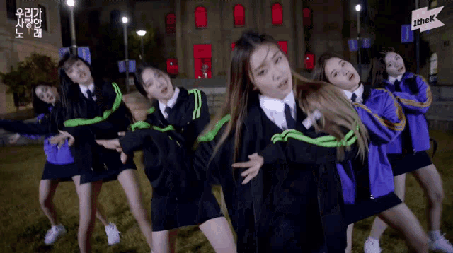 a group of girls are dancing in front of a building with the k logo on it