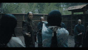 a group of people are standing around a woman with a sword in her hand