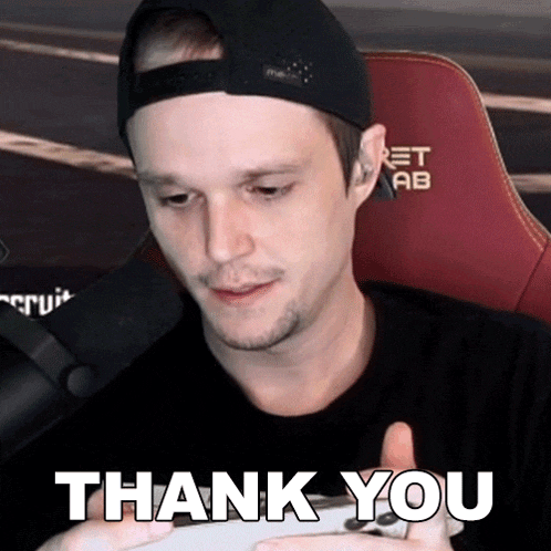 a man in a hat is holding a game controller and says " thank you "