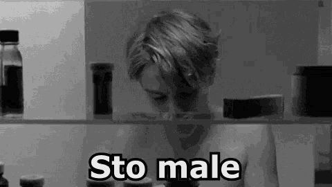 a black and white photo of a shirtless man looking through a refrigerator door with the words sto male written on it .