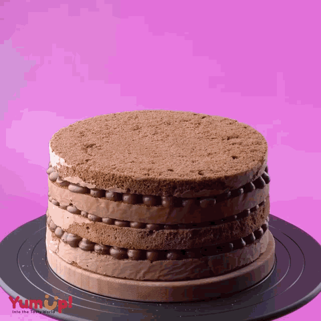 a chocolate cake is sitting on a black plate that says yum up on it