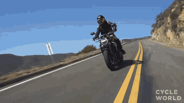 a person riding a motorcycle on a road with cycle world written on the bottom right