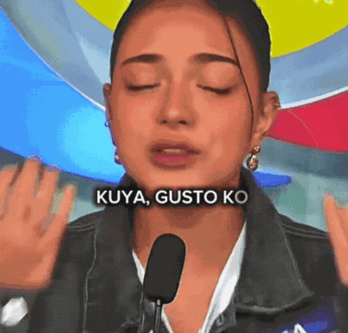 a woman is talking into a microphone and the words kuya gusto ko are on her face