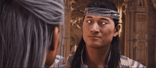 a man with long hair and a headband on his head is looking at another man .