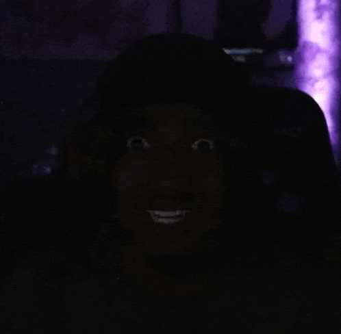 a close up of a person 's face in the dark with a purple background .
