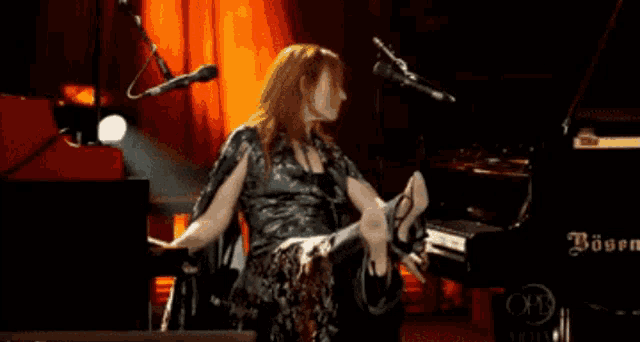a woman in a green dress is sitting at a piano with a microphone in front of her
