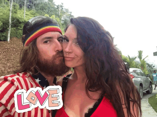 a man with a beard kisses a woman on the cheek with a sticker that says love
