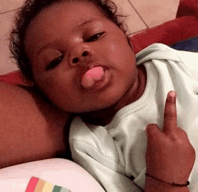 a baby is sticking out his tongue while giving the middle finger