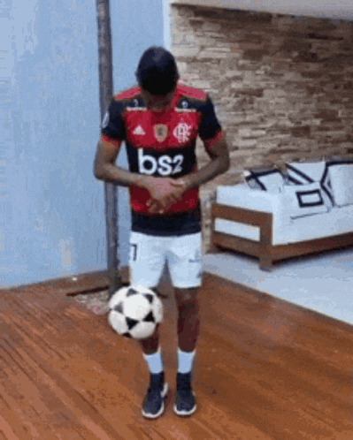 a man in a bs2 jersey is kicking a soccer ball on the floor