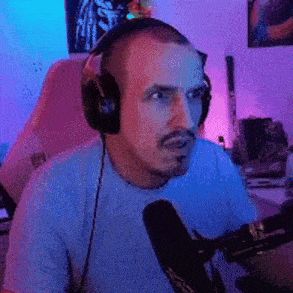a man wearing headphones and a mustache is sitting in front of a microphone in a room .