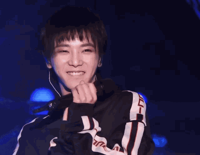 a young man holding a microphone and smiling with chinese writing behind him