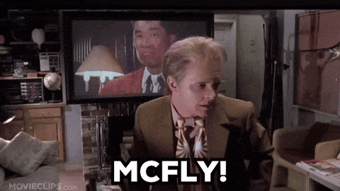 a man in a suit and tie says " mcfly " in front of a television