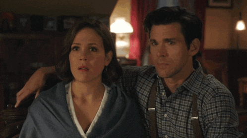 a man and a woman are sitting next to each other and the man has his arm around the woman 's shoulder